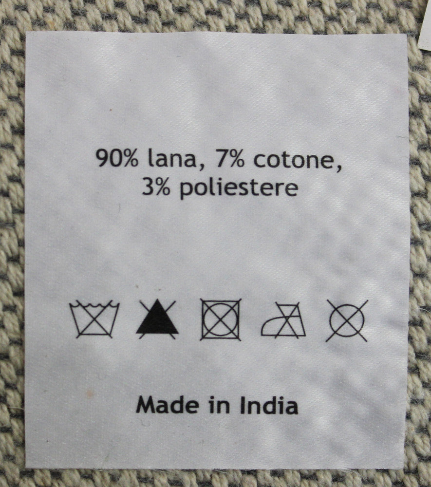 Etichetta del tappeto che riporta la composizione in lana, cotone e poliestere con la dicitura Made in India.