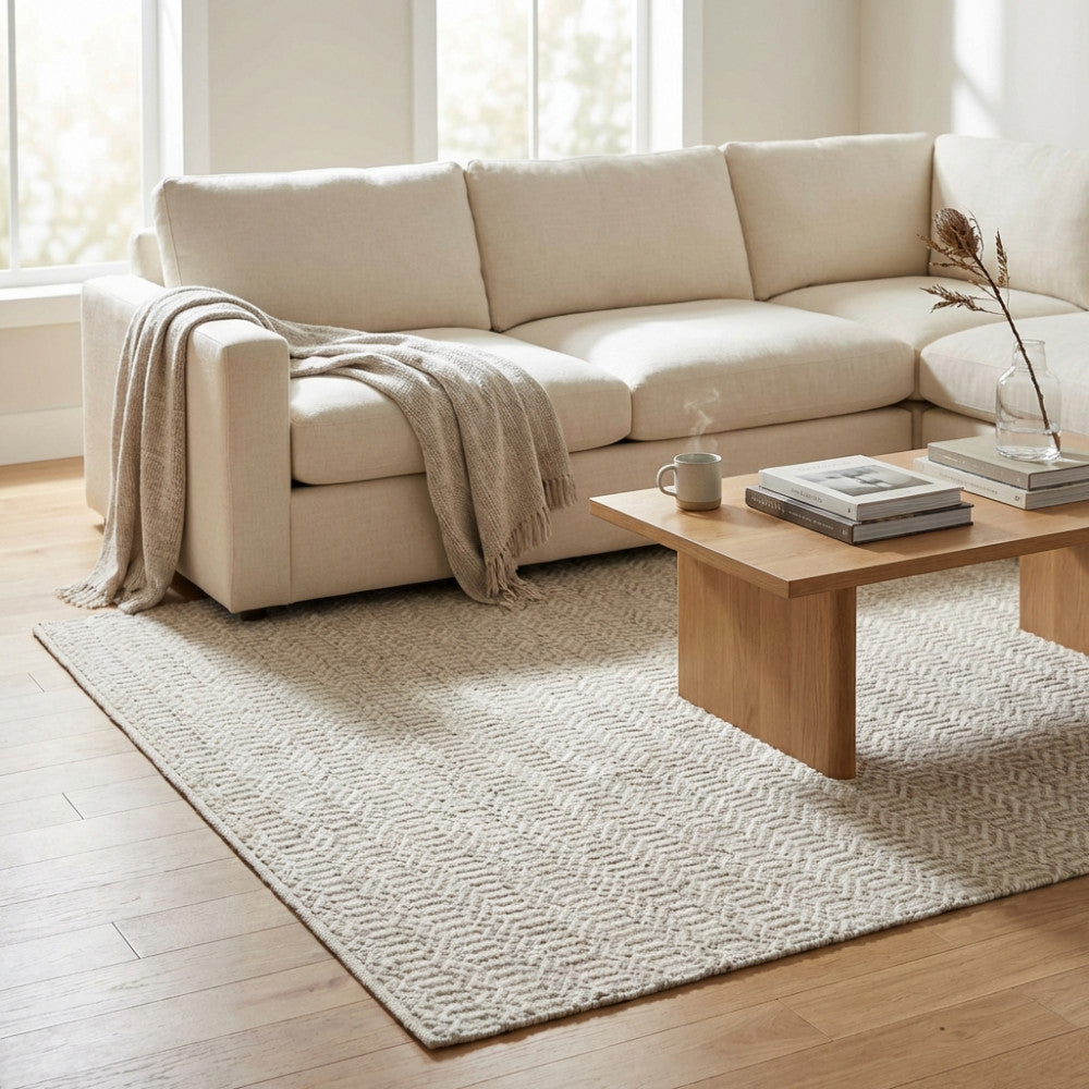 Dettaglio del tappeto Edgard nel living, abbinato a un divano componibile beige e un tavolino in legno minimalista.