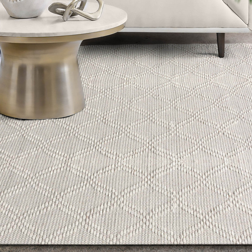 Primo piano della texture materica del tappeto in lana e cotone, con base di un tavolino in metallo dorato.