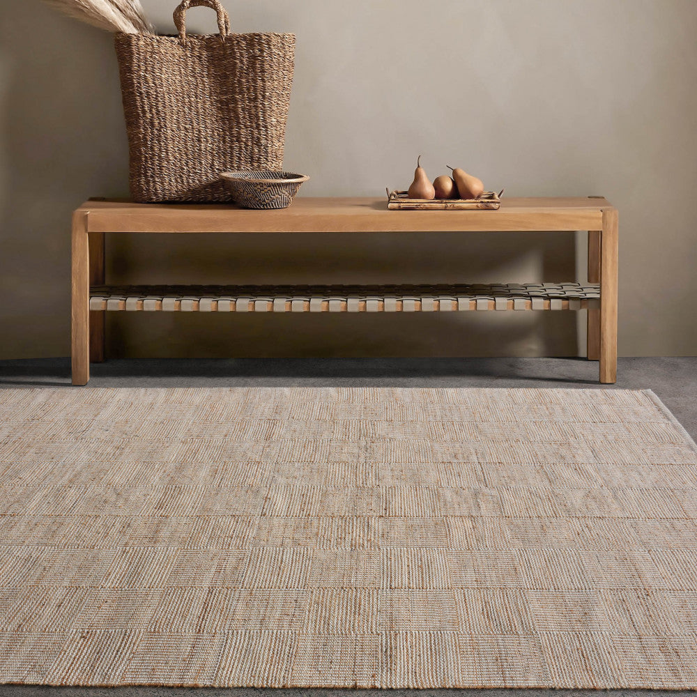 Il tappeto Eugène ambientato in un ingresso elegante con panca in legno e cesto in fibre naturali, esaltando le texture organiche.