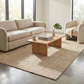Tappeto Eugène in lana e juta beige ambientato in un soggiorno moderno con divano chiaro e tavolino in legno.