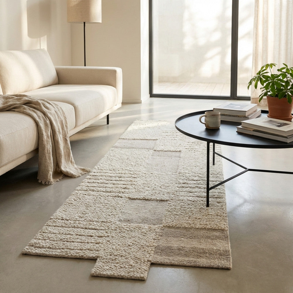 Tappeto Georges in lana e poliestere beige posizionato in un soggiorno moderno e luminoso con divano chiaro.