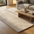 Tappeto Grégoire in lana e cotone bianco, steso in un living moderno illuminato dalla luce naturale con divano e tavolino in legno.