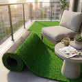 Rotolo di tappeto erboso sintetico verde srotolato su un balcone moderno con poltrona e tavolino.
