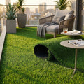 Tappeto erboso sintetico steso su un balcone moderno con poltrona in corda e tavolini di design.