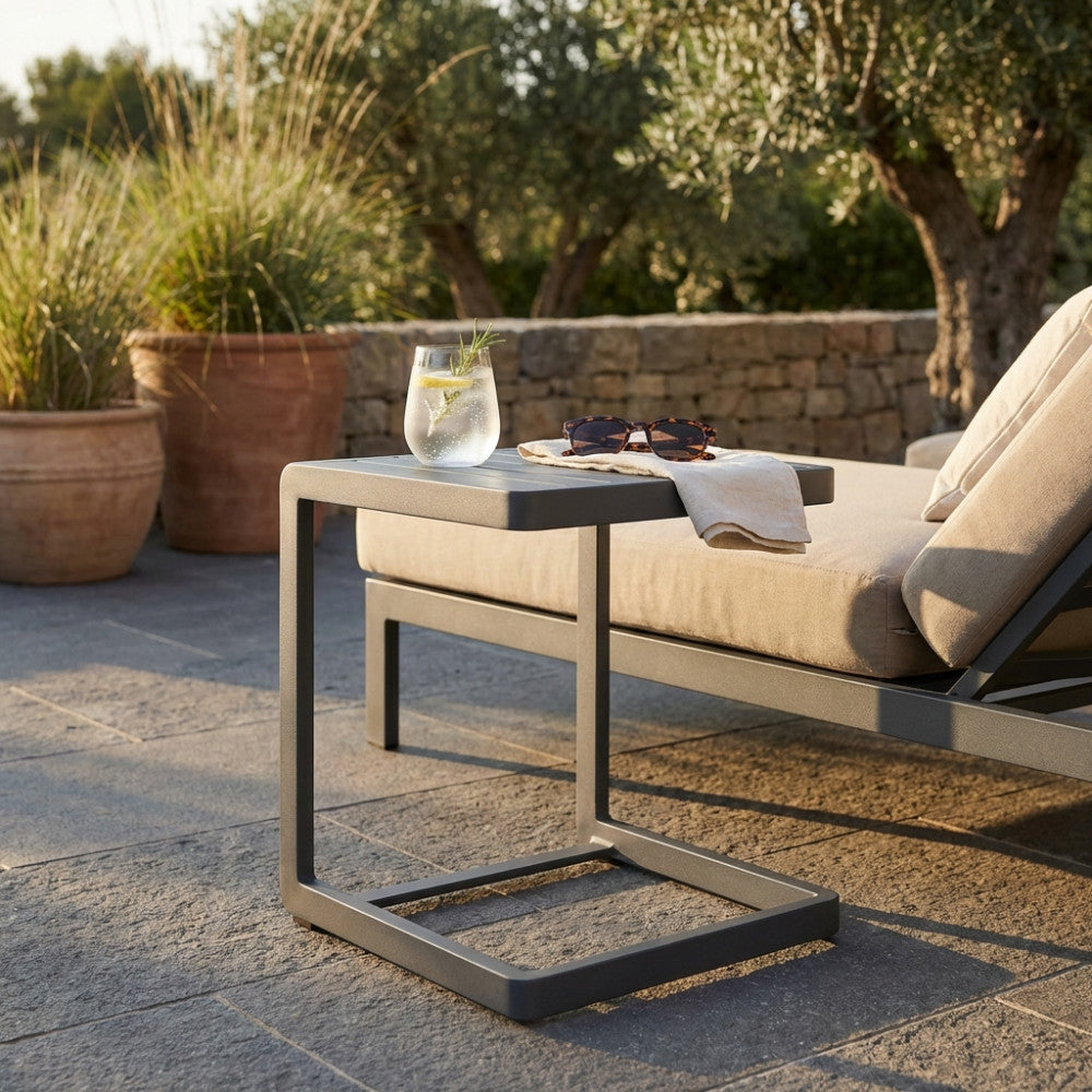 Tavolino da giardino Alimos in alluminio antracite posizionato accanto a un divano outdoor con bicchiere.