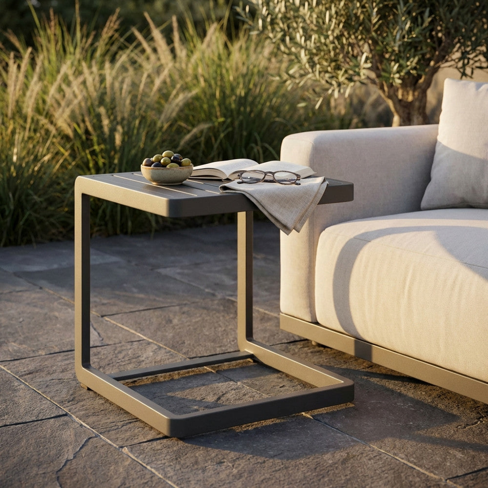 Dettaglio del tavolino da giardino Alimos a forma di C con libro e occhiali su un patio in pietra.