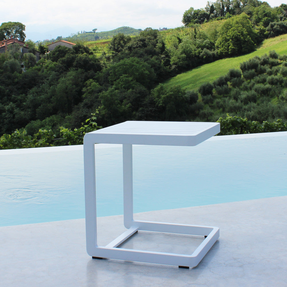 Tavolino da giardino in alluminio bianco posizionato a bordo piscina con vista panoramica