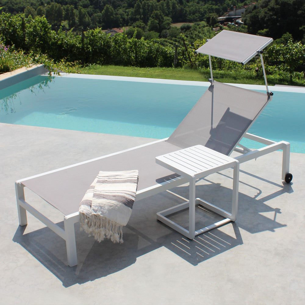 Tavolino Alimos in alluminio bianco abbinato a un lettino prendisole a bordo piscina