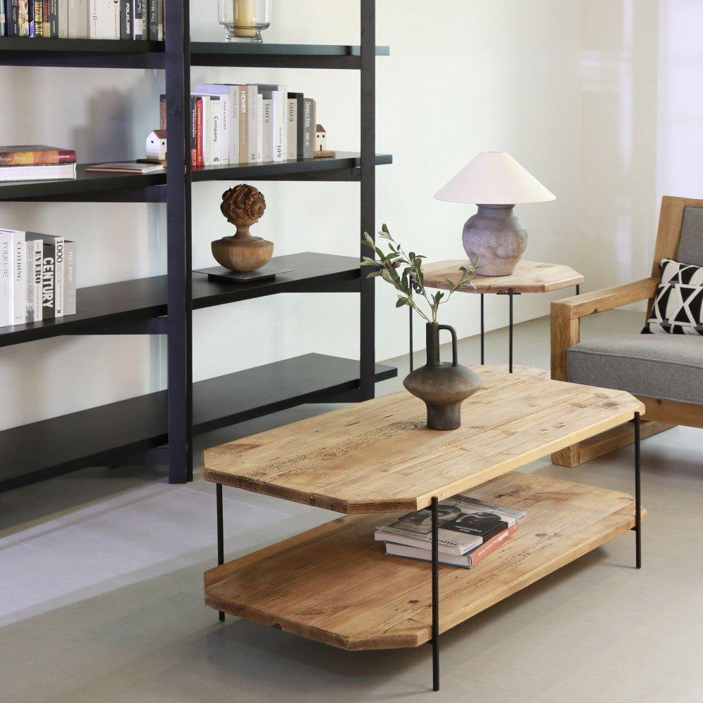 Ambientazione elegante con il tavolino in legno al centro, circondato da librerie nere e vasi in ceramica.
