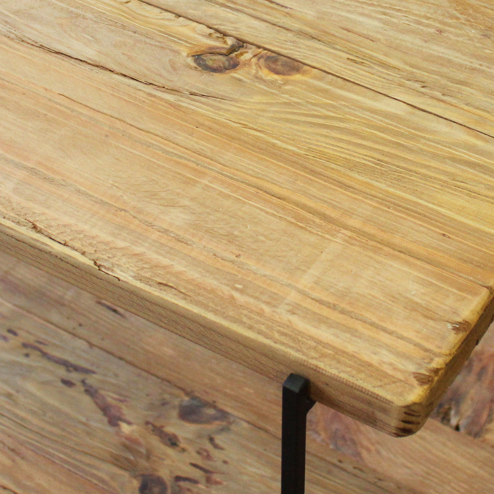Primo piano estremo della giunzione tra il legno rustico e la gamba in metallo nero.