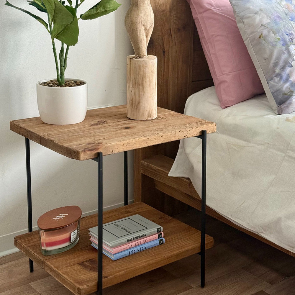 Dettaglio del ripiano in legno del tavolino con libri di moda e pianta decorativa.