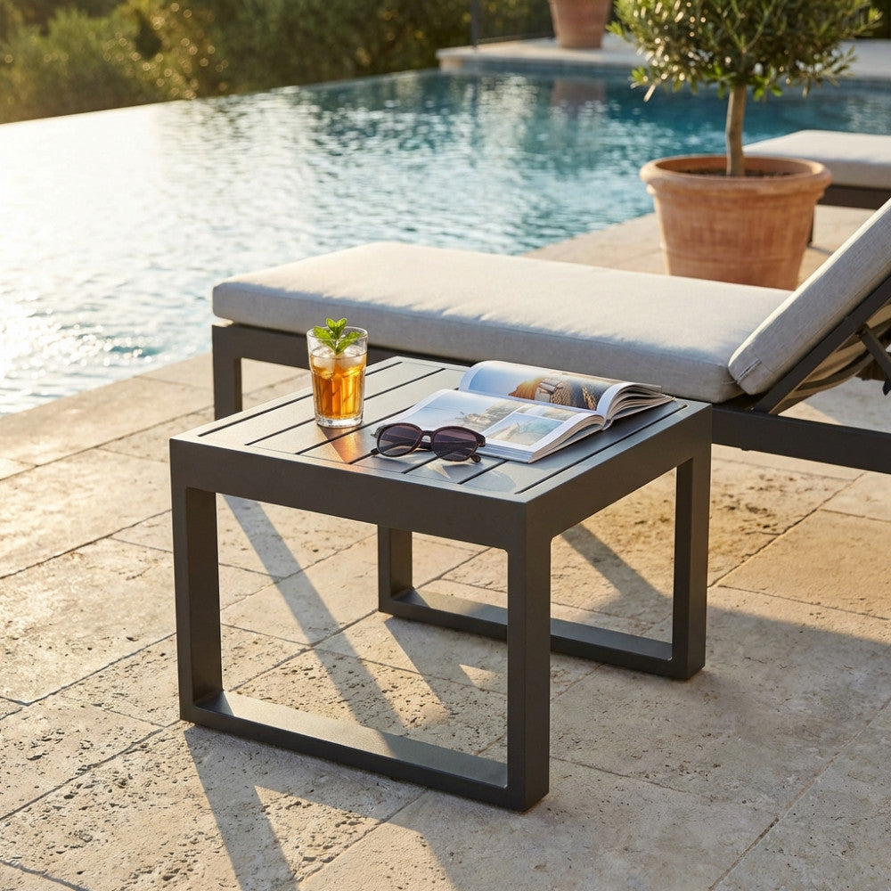 Tavolino da giardino Cuba in alluminio antracite a bordo piscina con drink e rivista.