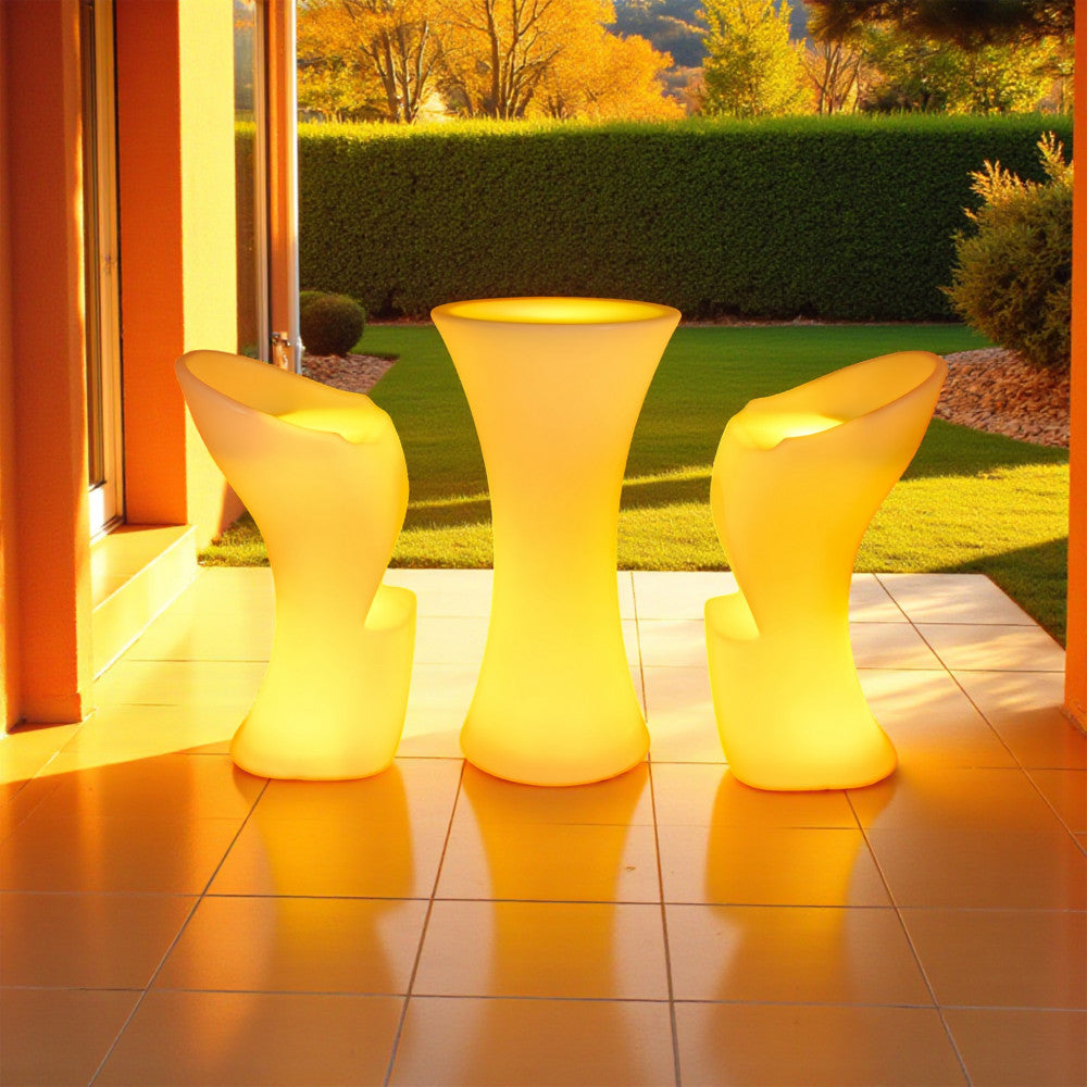 Set di arredi luminosi con il tavolino Perseus e sgabelli abbinati illuminati di giallo in un patio soleggiato.