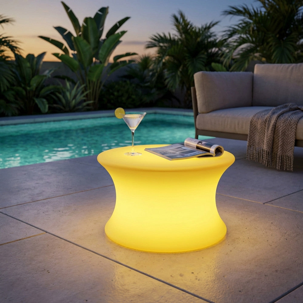 Tavolino luminoso Pegasus acceso al tramonto vicino a una piscina, creando un'atmosfera rilassante.