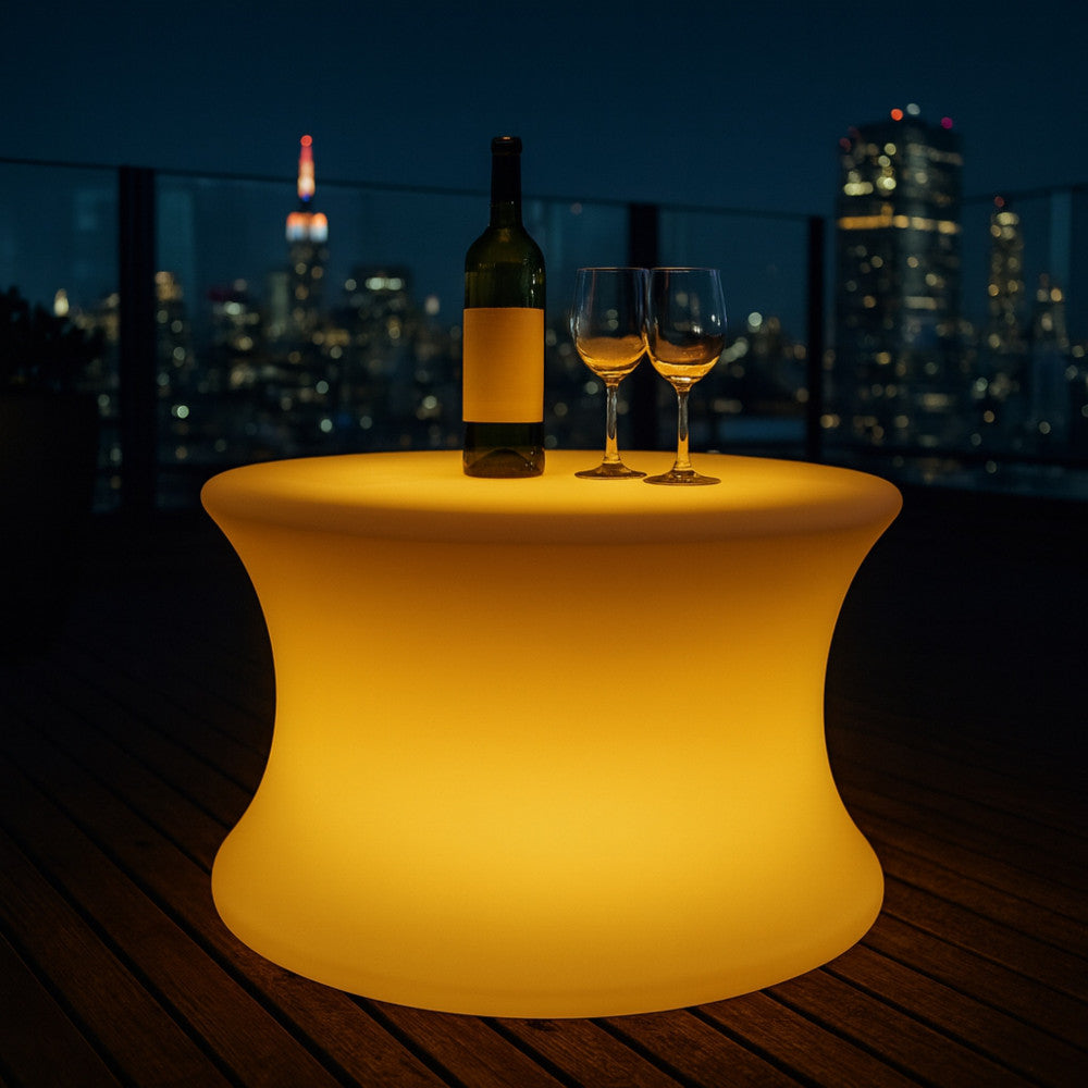 Tavolino luminoso Pegasus su una terrazza panoramica notturna con vista sullo skyline della città.