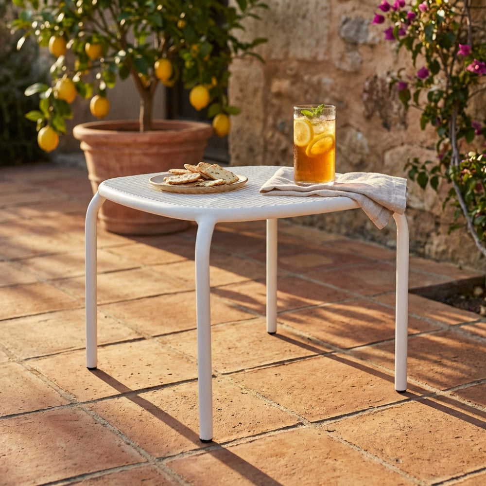 Tavolino da giardino Midway in acciaio bianco, allestito su un patio in cotto con un drink rinfrescante e stuzzichini, circondato da piante di limoni.