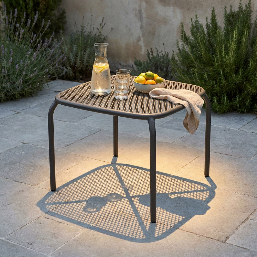 Tavolino da esterno Midway in metallo traforato, decorato con una caraffa d'acqua, bicchieri e limoni freschi in un patio soleggiato.