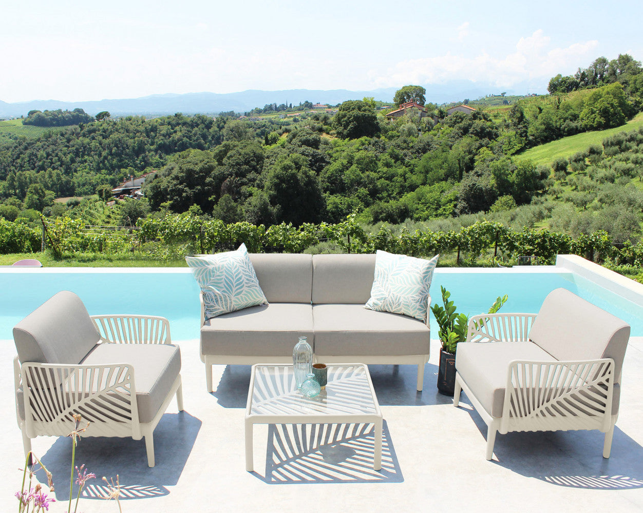 Set lounge completo Guaranà con divani e tavolino centrale in polipropilene tortora su una terrazza panoramica.
