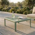 Tavolino da salotto Guaranà in polipropilene verde oliva ambientato in un giardino moderno con luce naturale.