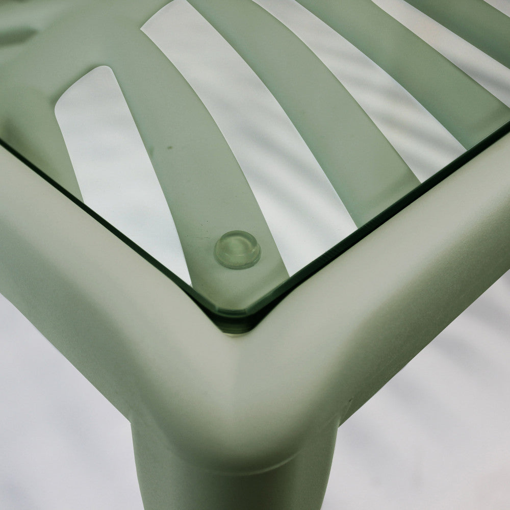Dettaglio strutturale del tavolino Guaranà che mostra il piano d'appoggio trasparente e i supporti in silicone.