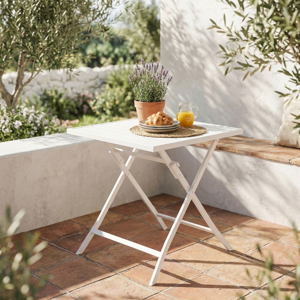 Tavolo da giardino Alabama in alluminio bianco allestito per la colazione su un patio soleggiato con pavimentazione in cotto.