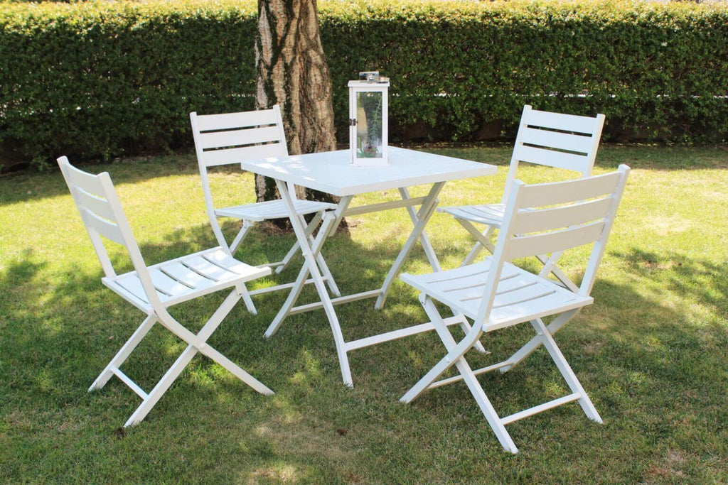 Set completo da esterno con il tavolo Alabama e quattro sedie pieghevoli abbinate, disposti su un prato verde all'ombra di un albero.