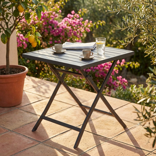 Tavolo da giardino Alabama in alluminio taupe allestito su un patio in cotto con tazzine da caffè e limoni sullo sfondo.