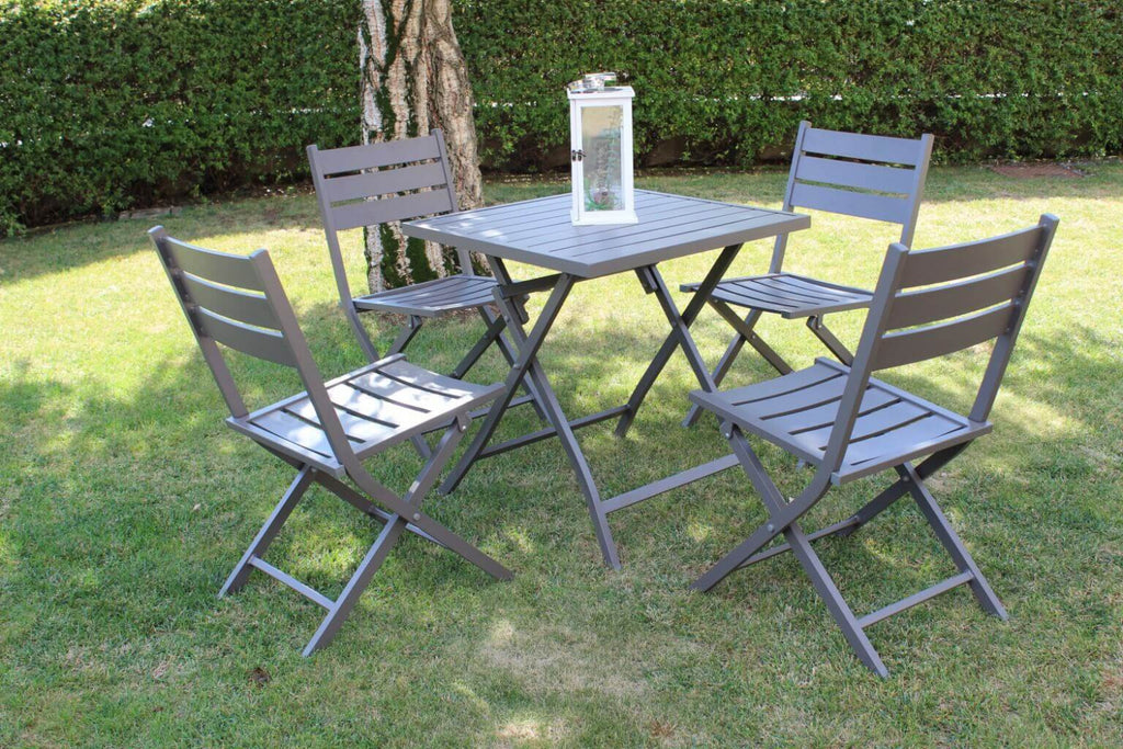 Set completo outdoor con il tavolo Alabama e quattro sedie coordinate in alluminio taupe, disposti su un prato verde curato.