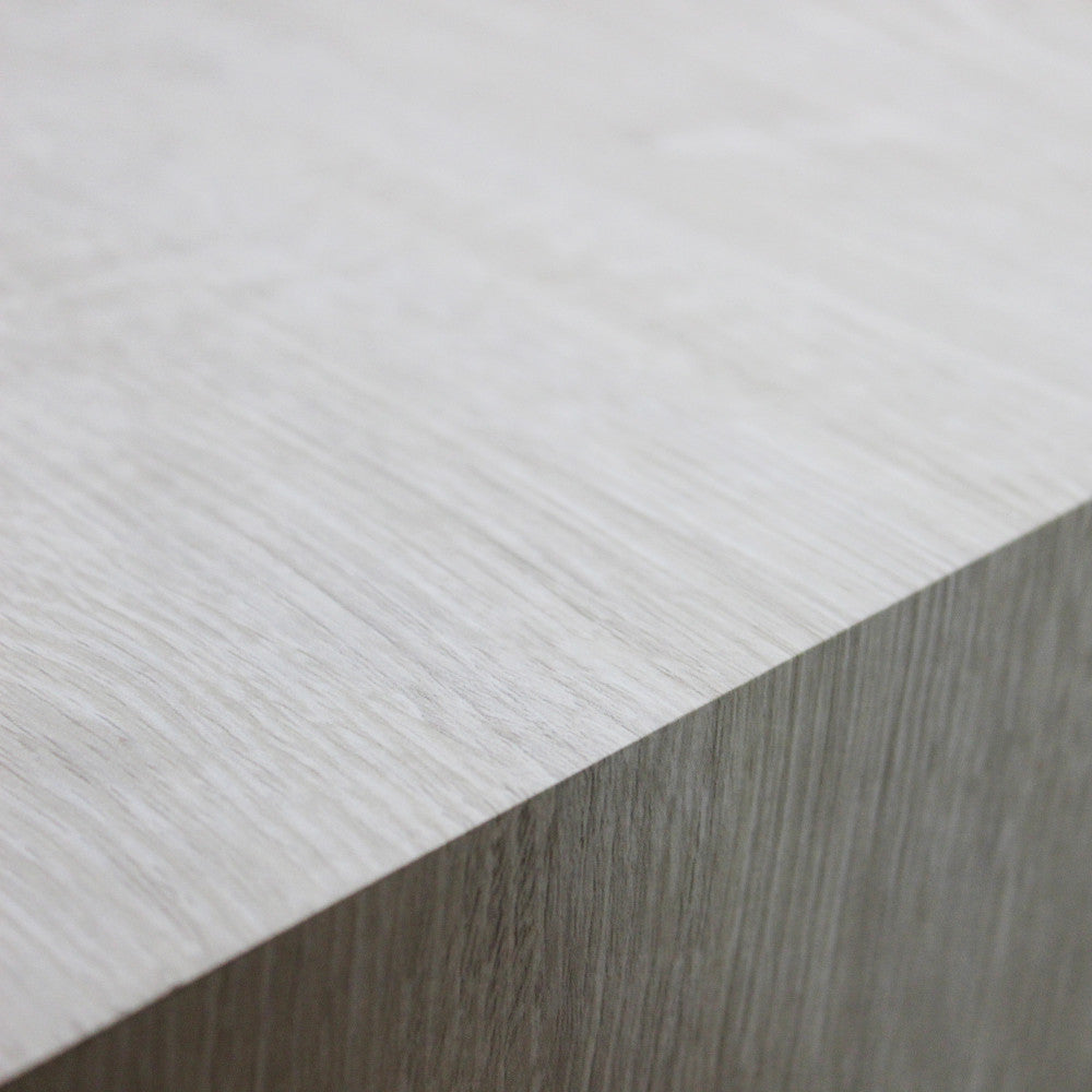 Dettaglio ravvicinato della texture tattile in melaminico bianco effetto legno del piano.