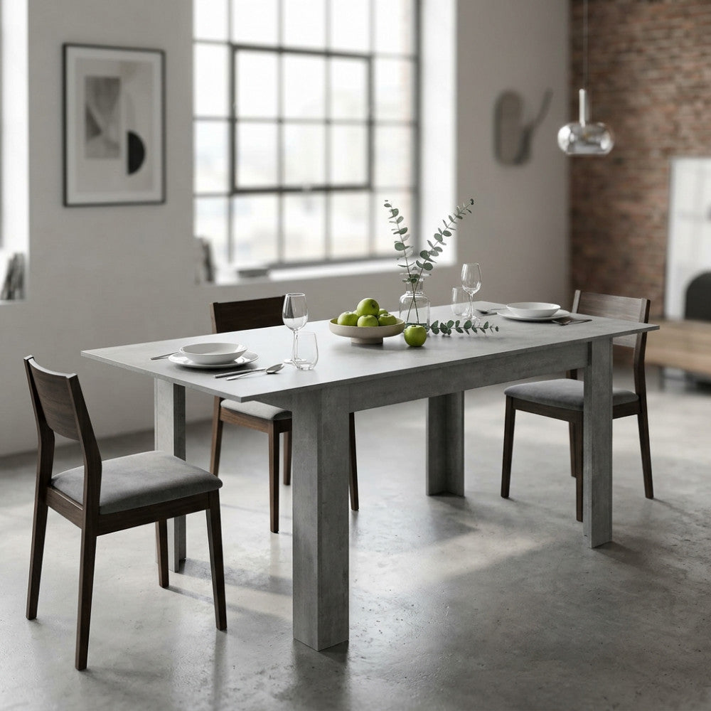 Tavolo da pranzo allungabile Emmet grigio effetto cemento ambientato in una sala da pranzo moderna con sedie in legno.