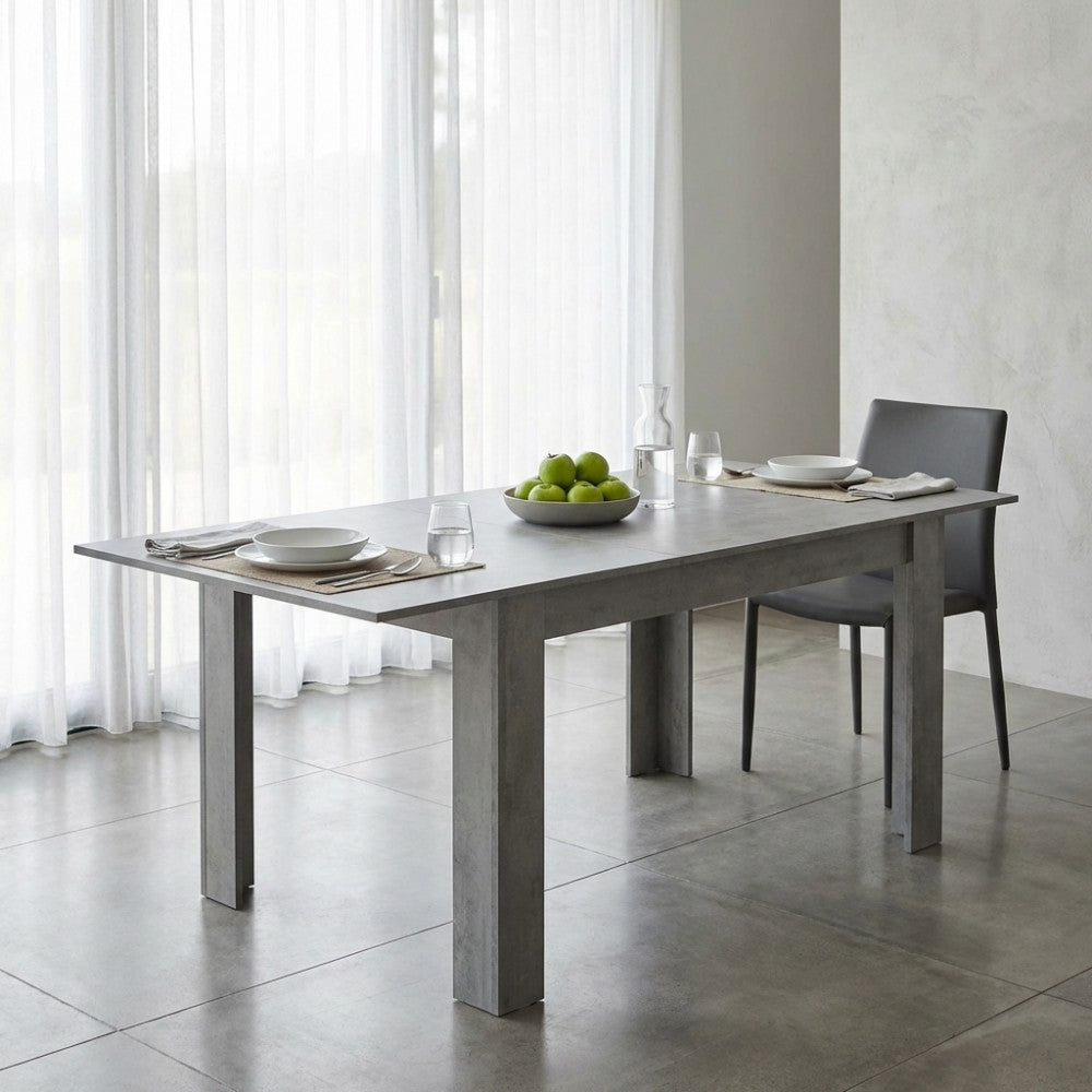 Tavolo Emmet in melaminico grigio in un ambiente luminoso e minimalista con tende bianche.