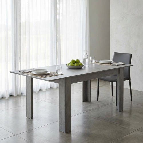 Tavolo Emmet in melaminico grigio in un ambiente luminoso e minimalista con tende bianche.