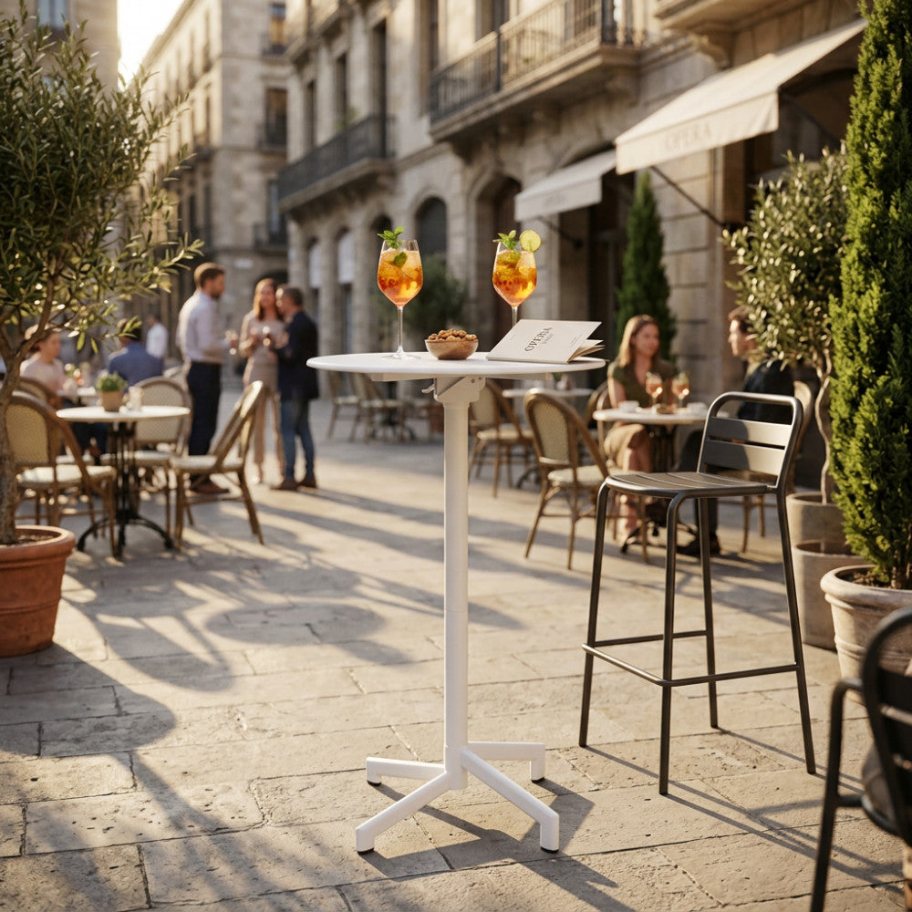 Tavolo alto VEGA Ø 60 in acciaio bianco ambientato in un elegante dehor cittadino con cocktail.