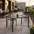 Tavolo da giardino in metallo antracite allestito per una cena elegante su una terrazza al tramonto.