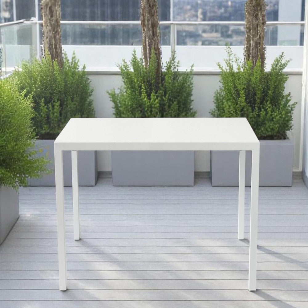 Dettaglio del tavolo rettangolare bianco posizionato su una terrazza moderna con piante decorative.