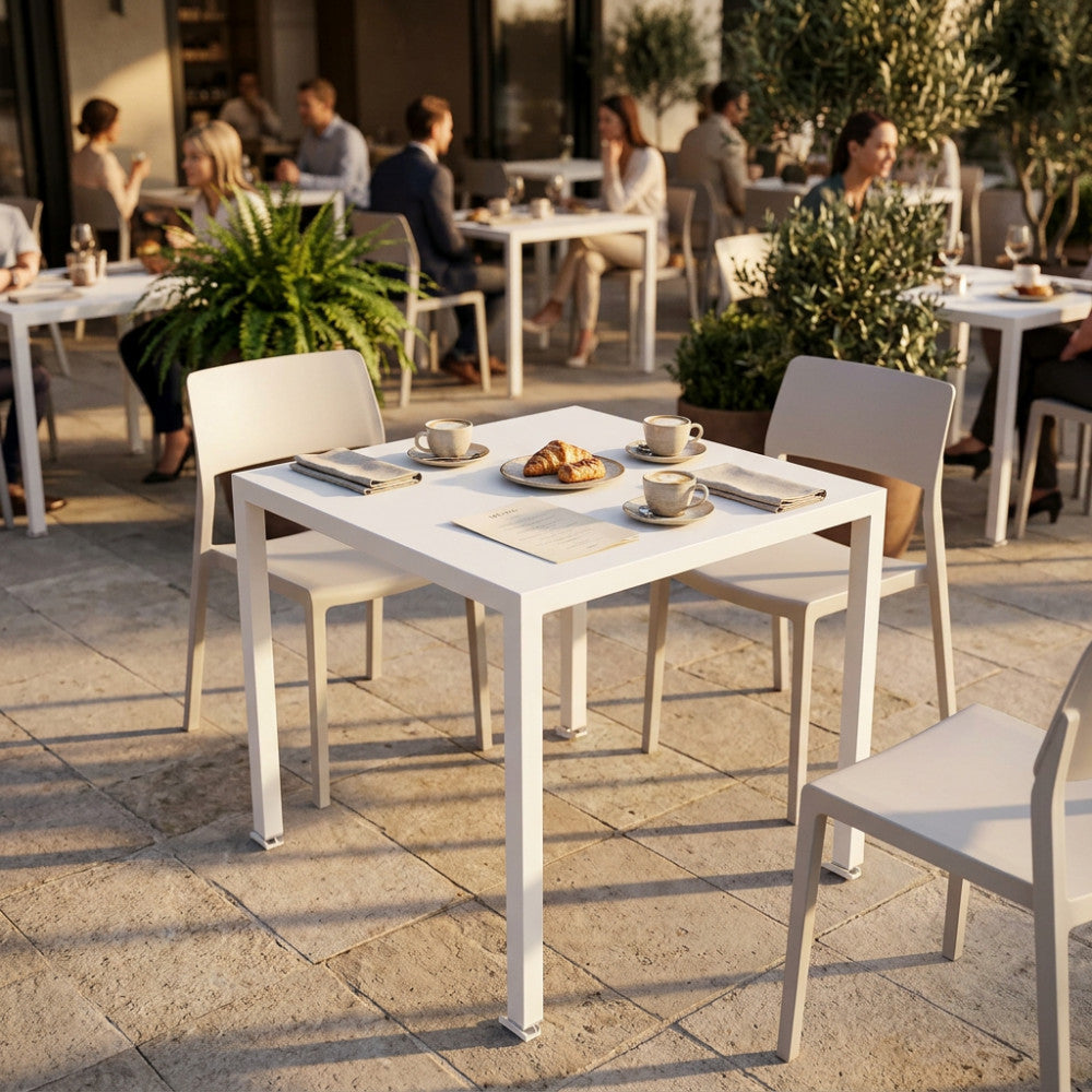 Il tavolo da giardino autolivellante in metallo bianco allestito con caffè e pasticcini in un soleggiato caffè all'aperto.
