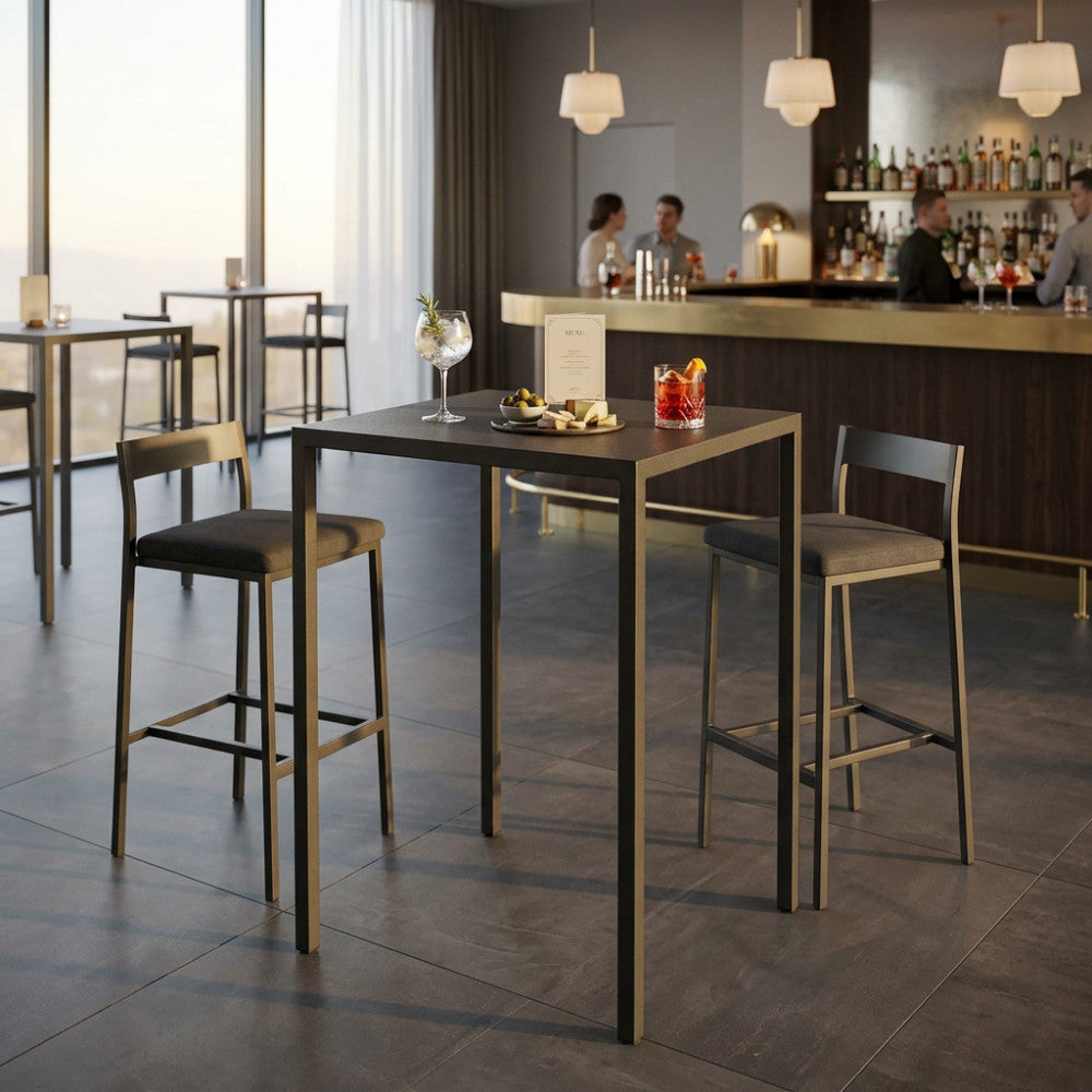 Un elegante ambiente bar interno con il moderno tavolo alto autolivellante, abbinato a sgabelli imbottiti e cocktail sofisticati.