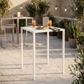 Tavolo da giardino autolivellante in metallo bianco allestito per un aperitivo su un patio soleggiato.