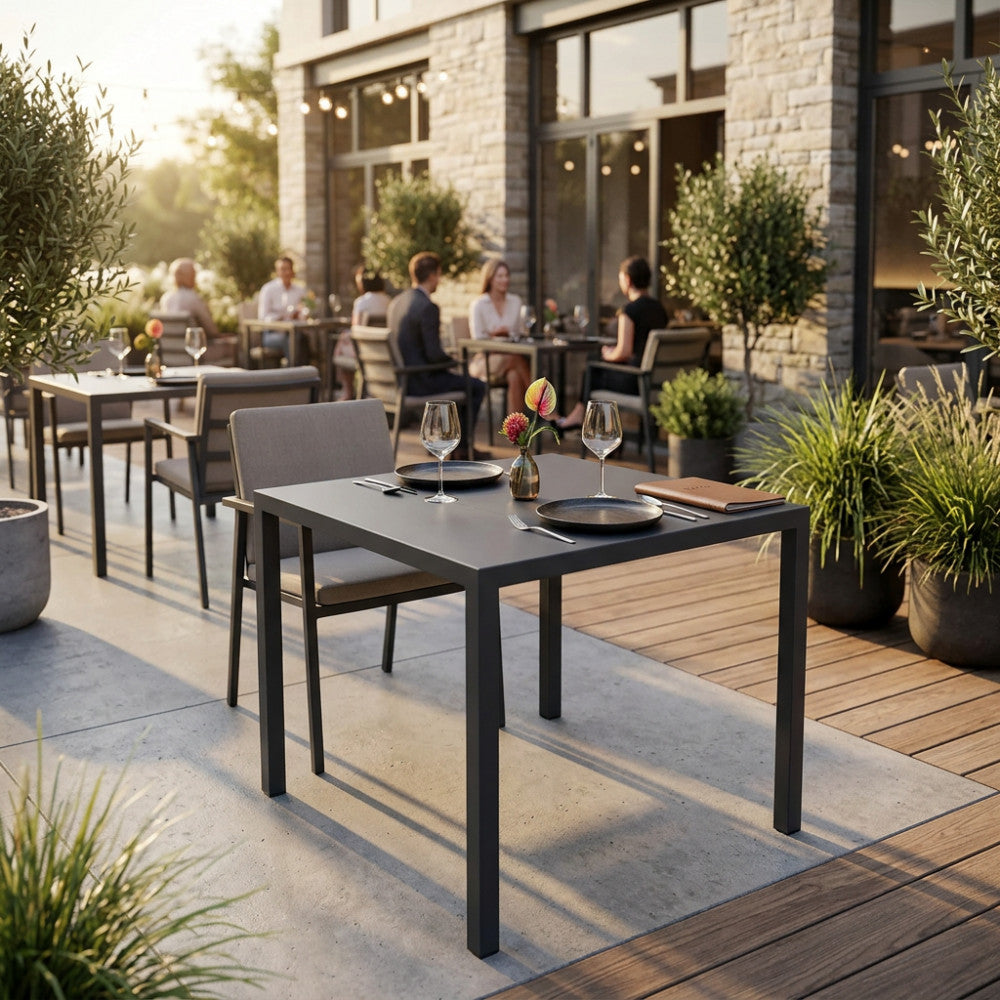 Tavolo da giardino autolivellante in metallo antracite allestito su una terrazza elegante al tramonto.