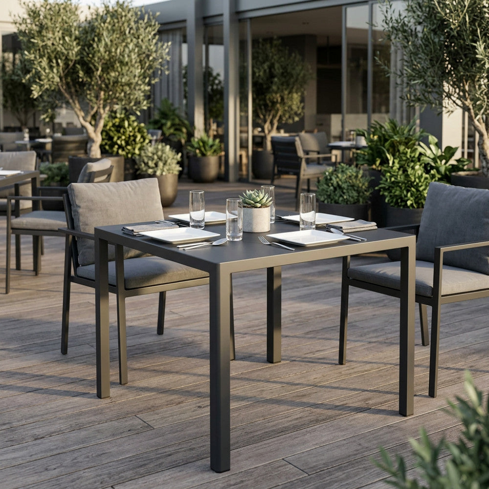 Dettaglio del tavolo da giardino quadrato 80x80 cm in metallo con sedute abbinate in un patio moderno.