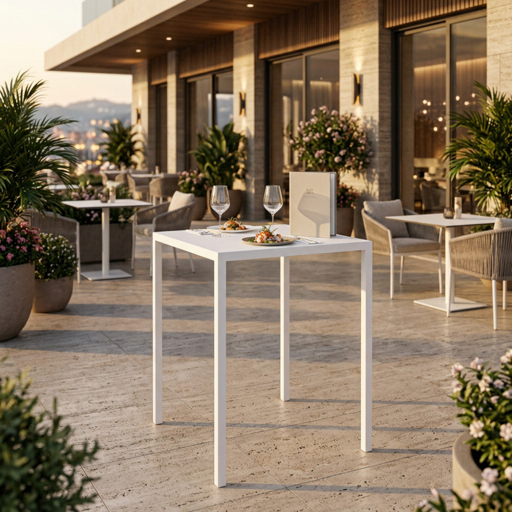 Tavolo da giardino autolivellante in metallo bianco allestito su una terrazza di lusso al tramonto.