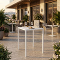Tavolo da giardino autolivellante in metallo bianco allestito su una terrazza di lusso al tramonto.