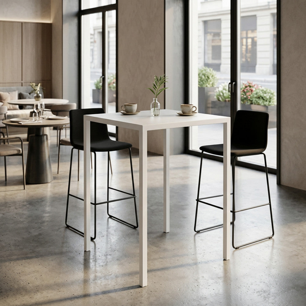 Tavolo alto moderno in metallo bianco abbinato a sgabelli neri in un elegante bistrot contemporaneo.
