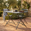 Tavolo da giardino Bristol in acciaio taupe allestito su un patio in cotto con sedute abbinate.