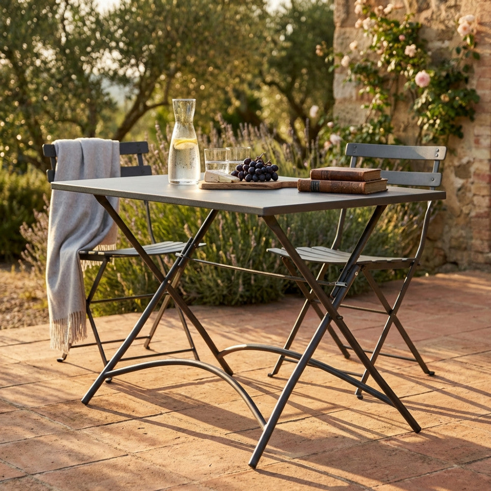 Tavolo da giardino Bristol in acciaio taupe allestito su un patio in cotto con sedute abbinate.