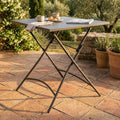 Tavolo da giardino Bristol in acciaio taupe allestito per la colazione su un patio in cotto.