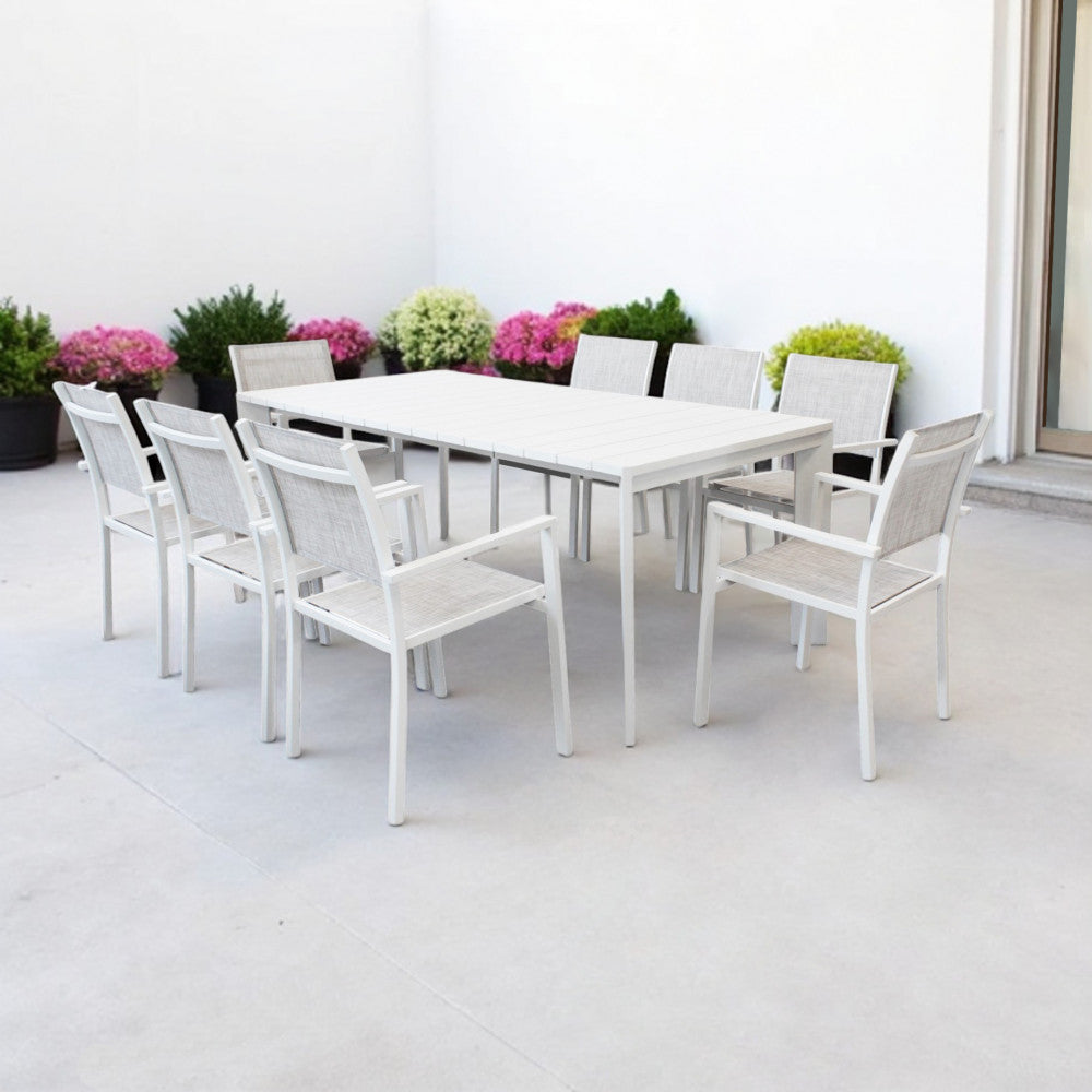 Tavolo Brooklyn circondato da otto sedie in alluminio bianco con sedute in tessuto grigio in un ambiente moderno.