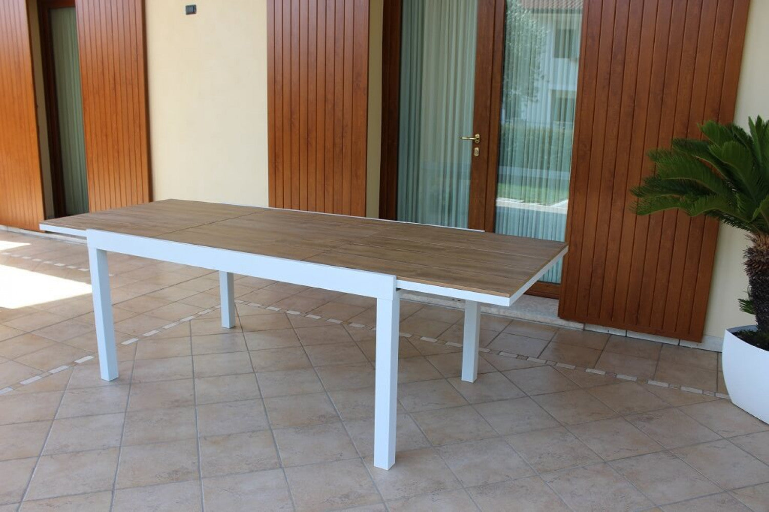 Tavolo da giardino allungabile Cayman completamente esteso su un patio piastrellato.