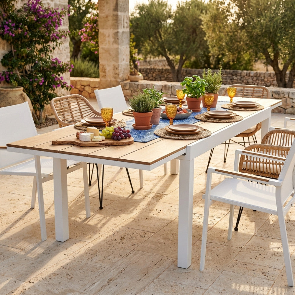 Tavolo Cayman allestito per un pranzo all'aperto con sedute in corda e stoviglie eleganti.